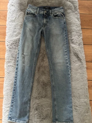 Blå raka jeans från Replay - Säljer ett par klassiska blå jeans från Replay med raka ben och snyggt slitna detaljer. Jeansen har fem fickor och normal midja. Perfekta till en avslappnad stil och tillverkade i mjukt denimtyg.