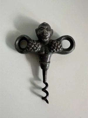 Unik Bacchus korkskruv i tenn (1920-1930-tal) - Unik antik korkskruv i tenn föreställande den glade vinguden Bacchus klädd i druvklasar. Ikonisk korkskruv som var populär på 1920- och 1930-talet och nu en tidlös klassiker. Ett vinoffer till Bacchus sägs ge god skörd, berusande glädje och mental frigörelse från vardagens bekymmer. Kbk!