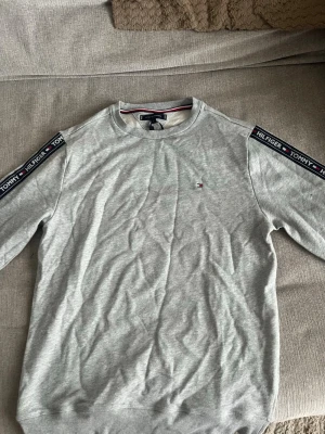 Grå sweatshirt från Tommy hilfiger  - En helt ny sweatshirt från Tommy hilfiger, prislappen sitter kvar på tröjan som ni kan se på sista bilden. Säljer då den inte har kommit till användning. Priset är inte hugget i sten och kan gå ner vid en snabb och smidig affär! Köparen står för frakten😁