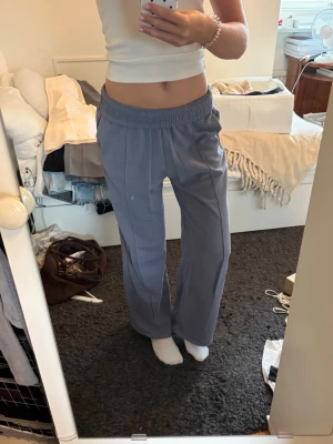Blå mjukisbyxor från Tezenis - Säljer ett par blå mjukisbyxor från Tezenis med bred resår i midjan och raka ben. Byxorna har en mjuk insida och är perfekta för chill dagar. Materialet är bomullsmix som känns skönt mot huden. Snygg söm framtill på benen för extra detalj.