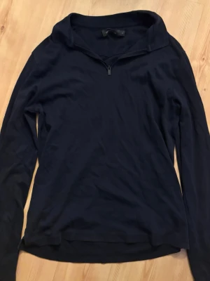 Marinblå halvzip tröja från Dressmann - Mörkblå långärmad tröja från Dressmann med halv dragkedja framtill och hög krage. Perfekt för lager på lager och enkel att matcha med olika outfits. Tillverkad i mjukt och bekvämt material. Har sug den på magen men synns knappt. Nypris 500kr