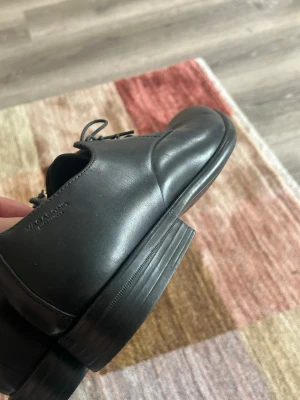 Svarta loafers i skinn från Vagabond - Stilrena svarta loafers från Vagabond i slätt skinn. Skorna har rundad tå, låg klack och klassisk design med snörning. Perfekta för dig som gillar en enkel men snygg look. Passar till många olika outfits. Använda 1 gång på balen