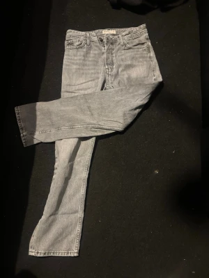 Ljusgrå raka jeans - Säljer ett par ljusgrå jeans med rak passform och klassisk femficksdesign. Jeansen har normal midja och är tillverkade i denim. Perfekta för en avslappnad och trendig look.