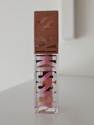 Maybelline Sky KISS 05 Blazing Blush - Använd två gånger. Rouge från Maybelline i nyansen 05 Blazing Blush. Färgen är en varm, rosabrun ton som ger en naturlig glow till kinderna. Kommer i en kompakt fyrkantig plastförpackning med genomskinligt lock och tryckt text i rosa och guld. Perfekt för att skapa en fräsch look.