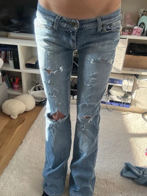 Big star Ljusblå slitna bootcut jeans - Säljer ett par ljusblå bootcut jeans med flera slitningar och hål på benen. Jeansen har låg midja och klassisk femficksmodell. Perfekta för dig som gillar en avslappnad och trendig stil. Storlek S! 