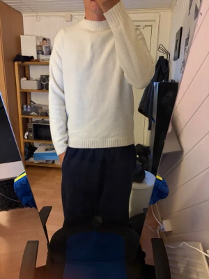 Vit stickad tröja Uniqlo - Klassisk vit stickad tröja från Uniqlo med rund halsringning och ribbade muddar vid ärmslut och nederkant. Enkel och stilren design som passar till det mesta. Perfekt för lager på lager under kyliga dagar.