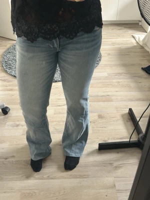 Ljusblå bootcut jeans - Säljer ett par ljusblå bootcut jeans med klassisk femficksmodell och är low waist. Jeansen har en avslappnad passform över låren och lätt utsvängda ben. Perfekta till sneakers eller boots och tillverkade i mjukt denimtyg.