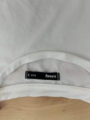 Vit topp från Sinsay med snörning - Säljer en vit topp från Sinsay i storlek S. Toppen har en enkel och stilren design med snörningsdetalj i sidan som ger en snygg twist. Tillverkad i ett mjukt och stretchigt material som sitter bekvämt på kroppen. Perfekt att matcha med jeans eller kjol.