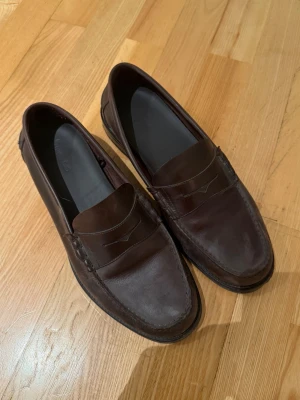 Loafers  - Säljer ett par mörkbruna loafers i äkta läder med klassisk pennyloafers-design. Skorna är från Massimo dutti och köptes där för 1800:- och är i size 42 och skulle säga att dem är tts.
