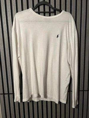 Vit långärmad tröja från Ralph Lauren - Klassisk vit långärmad tröja från Ralph Lauren använd 3 gånger. Har en liten fläck vid handen. (Den är väldigt oversized)
