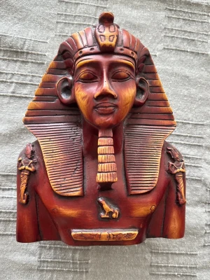 Farao byst i rödbrun resin - Dekorativ byst föreställande en egyptisk farao, tillverkad i rödbrun resin med detaljer i guldton. Bysten har klassiska egyptiska symboler och huvudbonad, och passar perfekt som prydnad eller samlarobjekt.