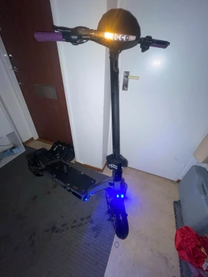 Kukirin G2  - Elektrisk scooter i svart med lila handtag och LED-belysning fram och bak. Scootern har robust ram i metall, stora hjul med skivbromsar och stötdämpare bak. Perfekt för smidig transport i stan och har en modern, sportig design.