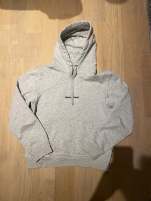 Ljusgrå hoodie Originals Studio - Ljusgrå hoodie med broderad text 'Originals Studio' på bröstet. Klassisk modell med stor huva och dragsko, samt magficka framtill. Tillverkad i mjukt sweatshirtmaterial som är perfekt för chill dagar. Enkel och stilren design som passar till det mesta. Vid en snabb affär kan priset diskuteras.