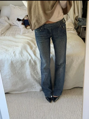 Mörkblå raka jeans med låg midja - Säljer ett par mörkblå jeans med rak passform och låg midja. Jeansen har klassiska fem fickor och snygga slitningar vid bensluten.
