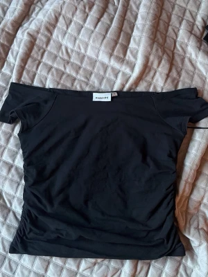 Svart offshoulder topp från Kappahl - Säljer en svart offshoulder topp från Kappahl i stretchigt material. Toppen har en tight passform och är perfekt för dig som gillar en enkel men snygg stil. Passar till många olika looks och är superenkel att matcha.
