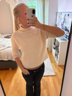 Vit stickad topp med halvpolo - Säljer en vit stickad topp med halvpolo och kortaärmar. Toppen är inte använd. Hör av dig om du har frågor