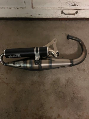 Yasuni Z slider - Säljer ett Vasuni avgassystem för moped. Utrustad med svart ljuddämpare och rostfri böjd pipa. Monteringsfäste i metall ingår. Passar perfekt för dig som vill uppgradera din moppe med snyggare och sportigare ljud.
