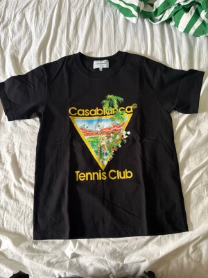 Svart Casablanca Tennis Club t-shirt - Säljer en svart t-shirt från Casablanca. Klassisk passform och rund hals. Perfekt för dig som gillar streetwear och vill sticka ut med en snygg grafisk detalj. Väldigt bra kvalite. 