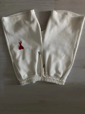 Vita ami Paris shorts - Säljer ett par vita mjukisbyxor med elastisk midja och benslut. Byxorna har en liten röd hjärtlogga framtill och en bakficka. Sköna och stilrena, perfekta för chill dagar. Materialet känns mjukt och bekvämt.