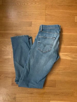 Ljusblå Levi ’s jeans - Säljer ett par ljusblå jeans med klassisk femficksdesign och raka ben. Jeansen har en avslappnad passform och är tillverkade i denim. Perfekta för en casual look och passar till det mesta i garderoben. Lite slitet runt fickorna och lite annorlunda form vid högerbakficka men inget som märks av. W31L34