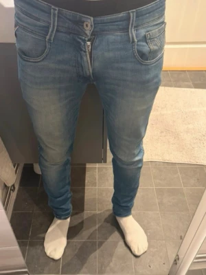 Blå slim fit jeans från Replay - Snygga blå slim fit jeans från Replay med klassisk femficksdesign och slitningar framtill. Jeansen har en något tvättad look och smala ben. Perfekta för dig som gillar en modern och avslappnad stil.