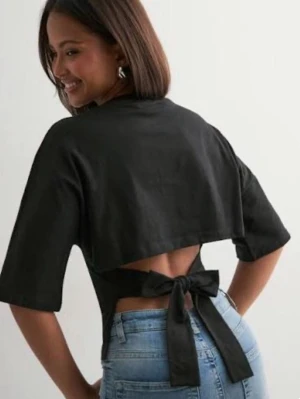 Svart croppad topp med knyt i ryggen - Snygg svart croppad topp med halvlånga ärmar och öppen rygg som knyts med en stor rosett. Toppen har en tight passform och är perfekt för dig som vill ha en trendig och unik look. Materialet ser ut att vara mjukt och följsamt. Säljer för att den inte används, skriv för mer bilder❤️