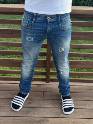 Blå slitna jeans från Replay - Säljer ett par blå jeans från Replay med slim fit och slitna detaljer på låren samt ljus tvätt. Jeansen är i väldigt bra skick! w29 L32 hör av dig vid minsta fundering!