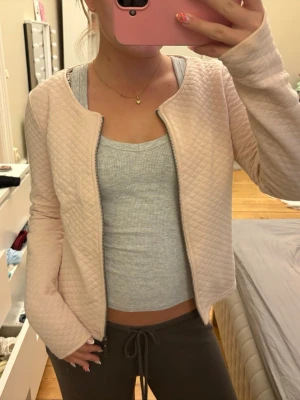 Ljusrosa cardiganjacka - Säljer en ljusrosa cardiganjacka med dragkedja framtill. Jackan har rundad halsringning och långa ärmar. Materialet är mjukt och lätt vadderat med ett rutmönster som ger en trendig look. Perfekt att slänga på sig över en topp💗