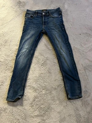 Mörkblå skinny jeans med slitningar - Säljer ett par mörkblå skinny jeans med lätt slitna detaljer och klassisk femficksmodell. Jeansen har en smal passform och normal midja. Materialet är denim med stretch för extra komfort. Perfekta för dig som gillar en enkel men snygg stil.