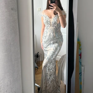 Silverglittrig långklänning med paljetter - Säljer en snygg långklänning i silver med glittriga paljetter. Klänningen har en figurnära passform, perfekt för bal eller fest.💕
