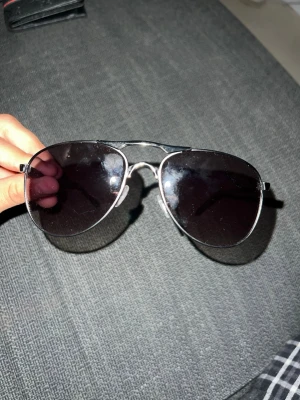 Svarta aviator solglasögon i metall - Snygga aviator solglasögon med svarta glas och silverfärgad metallbåge. Klassisk form som ger en cool vibe och passar perfekt till soliga dagar. Lätta att matcha med olika outfits och riktigt tidlösa.