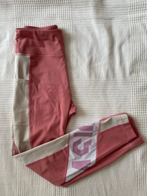 Asics träningstights - Träningstights från Asics med en ficka på ena benet. Har en fläck högst uppe i linningen (se bild 3).