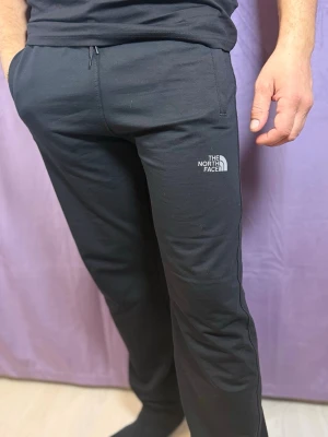 Svarta mjukisbyxor från The North Face - Säljer ett par svarta mjukisbyxor från The North Face med logga på vänster lår. Byxorna har en rak passform, dragsko i midjan och är gjorda i mjukt bomullsmaterial. Perfekta för chill eller träning.