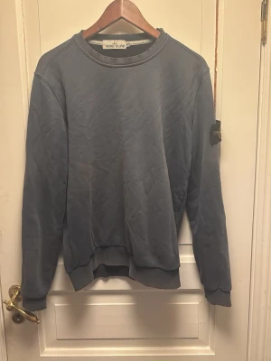 Stone island tröja - En stone island tröja i ganska slitet skick, sliten runt kragen och vid armbågarna(se bild 4) annars en snygg tröja som ser  bra ut med en skön outfit. Priset satt efter skick.