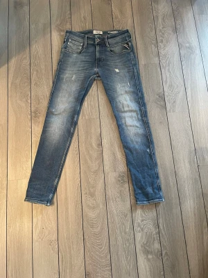 Blå slitna skinny jeans - Säljer ett par blå skinny jeans med slitningar och tvättade detaljer. Jeansen har fem fickor, dragkedja och knapp i midjan samt klassisk passform med smala ben. Materialet är denim i bomull. Perfekta för en avslappnad och trendig look. W27 L30 å pris kan diskuteras. Kom privat för mer frågor 