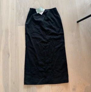 Svart långkjol i bomull - En stilren svart långkjol med rak passform. Kjolen är enkel och minimalistisk, perfekt att matcha med olika toppar. Tillverkad i mjukt bomullsmaterial som känns bekvämt mot huden.