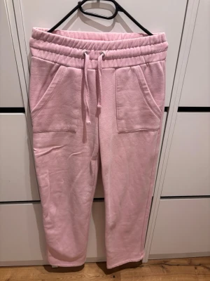 Ljusrosa mjukisbyxor med fickor XS - Säljer ett par ljusrosa mjukisbyxor med bred resår i midjan och dragsko. Byxorna har två stora fickor framtill och är gjorda i mjukt, skönt material. Perfekta för chill dagar hemma eller när du vill vara extra bekväm.