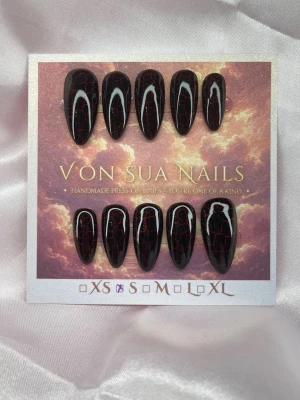Molten (S);Medium Almond - Unika handgjorda press-on naglar i svart med röda crackle-effekt i cateye, den röda cateyen syns under naglarna . Naglarna har en mefium lång,  almondform som ger en edgy look. Perfekt för dig som vill sticka ut med snygga och trendiga naglar.S: 15 mm, 11,5 mm, 12 mm, 11 mm, 9 mm 