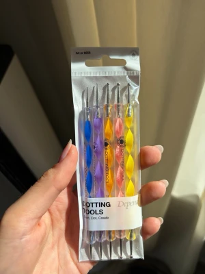 Färgglada dotting tools för naglar - Säljer ett set med fem dotting tools för nageldekoration. Handtagen är i plast med spiraldesign i blått, lila, orange, rosa och gult. Varje verktyg har metallspetsar i olika storlekar för att skapa prickar och mönster på naglarna. Perfekt för kreativ nail art och detaljerade designer.