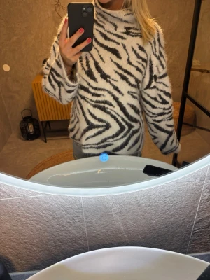 Zebramönstrad stickad tröja - Snygg stickad tröja med zebramönster i svart och vitt. Tröjan har hög krage och är tillverkad i ett mjukt, fluffigt material. Perfekt för dig som vill sticka ut med ett djurinspirerat plagg. Långärmad och avslappnad passform. Lånade bilder!💞