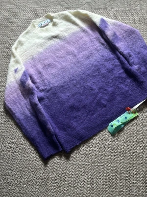 Off-White Sweater/tröja - Säljer en superfin stickad tröja av Off-Whitemed ombre-effekt i vitt och olika nyanser av lila. Tröjan har rund halsringning, långa ärmar och är gjord i ett fluffigt, mjukt material som känns lyxigt. Perfekt för höst/vinter och för dig som vill ha något unikt och trendigt i garderoben.