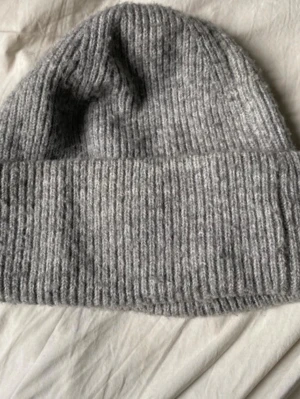 Grå ribbstickad mössa - Mysig grå mössa i ribbstickat material med bred uppvikt kant. Perfekt för kalla dagar och enkel att matcha med olika outfits. Klassisk modell som passar de flesta stilar.