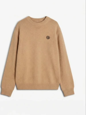 House of savoj Beige stickad tröja  - Snygg beige stickad tröja med rund hals och ribbade muddar. Tröjan har en liten broderad patch på bröstet och är tillverkad i mjukt material. Perfekt för lager på lager och enkel att matcha med olika outfits.