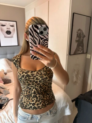 Leopardmönstrad croppad topp - Säljer en leopardmönstrad croppad topp med fyrkantig ringning och korta ärmar. Toppen har en tight passform och är perfekt för dig som vill sticka ut. Materialet känns mjukt och stretchigt, troligen polyester eller bomull.