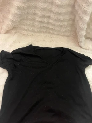 Svart v-ringad t-shirt från SHEIN - En enkel svart t-shirt från SHEIN med v-ringning och korta ärmar. Tillverkad i mjukt material som passar perfekt till alla outfits. Klassisk och stilren design som är lätt att matcha.
