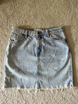 Ljusblå jeanskjol från Zara - Säljer en super fin jeanskjol från Zara. Den är ljusblå i färgen med lite slitningar. Inga tecken på användning, nyskick. 