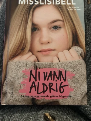 Ni vann aldrig av Misslisibell - Boken 'Ni vann aldrig' av Misslisibell, berättad för Pernilla Karlsson, handlar om att ta sig igenom högstadiet. Omslaget har en närbild på Misslisibell med rosa och svart text. Perfekt för dig som gillar självbiografiska berättelser. Har aldrig lästs men har stått framme så finns skavanker på omslaget
