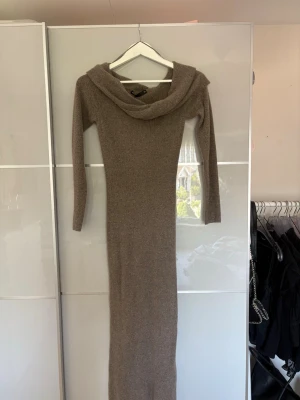 Beige lång stickad klänning - Mysig beige långklänning i stickat material med lång ärm och offshoulder. Perfekt för dig som vill ha en enkel men ändå snygg look. Passar till både sneakers och boots.