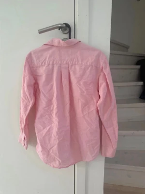 Rosa skjorta från Ralph Lauren - Säljer en klassisk rosa skjorta från Ralph Lauren i bomull. Skjortan har lång ärm, knappar framtill och en tidlös krage. Perfekt för dig som gillar en clean och stilren look.