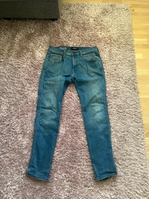 Replay Anbass Blå slim fit jeans  - Tja! Säljer nu snygga blå slim fit jeans från Replay i modellen Anbass. Knappt använda och i väldigt bra skick. Ända defekten som finns är att det är två vita prickar där jeansen har blivit blekta. Storleken är 33/32. Hör gärna av dig vid frågor och funderingar!🤩